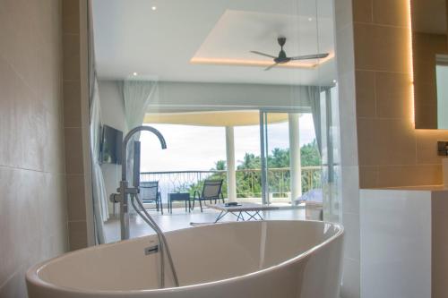 una bañera en un baño con vista a un balcón en Chaweng Noi Ocean View Villa, en Nathon Bay