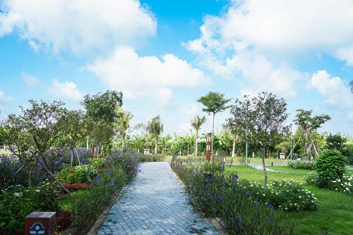 a garden with purple flowers and a pathway at VinaEcolife Lodge in Ba Tri