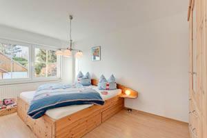 a bedroom with a bed with blue blankets and a window at Ferienhaus Ostseeblick in Göhren