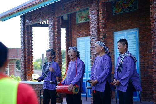 a group of men standing in front of a brick building at VinaEcolife Lodge in Ba Tri