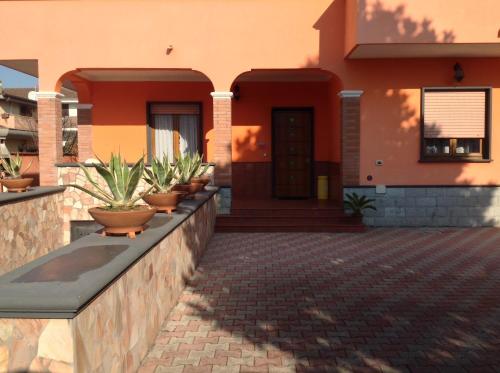 a house with a row of potted plants on a wall at Orange Holiday Home in Torvaianica