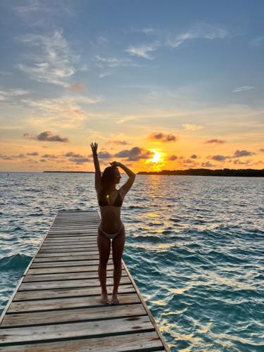 a woman standing on a dock in the water at sunset at Orika del Mar Hotel in Isla Grande