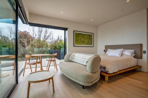 a bedroom with a bed and a chair and a table at Sky High Retreat in Nelson