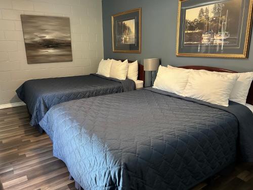 two beds in a room with paintings on the wall at Arrow Lake Motel in Fauquier