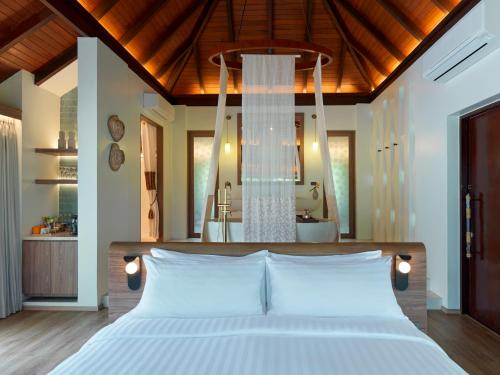 a bedroom with a white bed and a chandelier at Villa Zolitude Resort & Spa - SHA Extra Plus in Chalong 