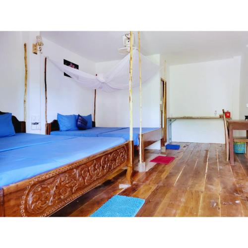 a bedroom with a canopy bed with blue sheets at Mangrove Beach Bungalows in Koh Rong Sanloem