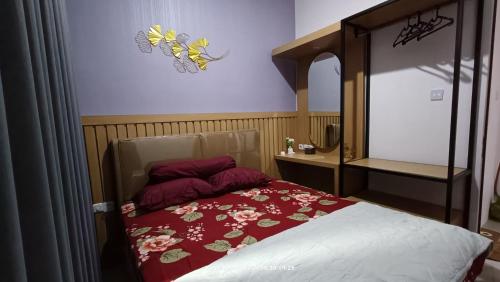 a bedroom with a bed with a red blanket and butterflies on the wall at Villa Naratetama in Batu