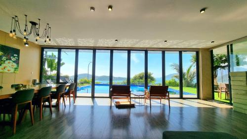 a dining room with a table and chairs and a pool at Anh Nguyen Oceanfront Luxury Villas Nha Trang in Nha Trang