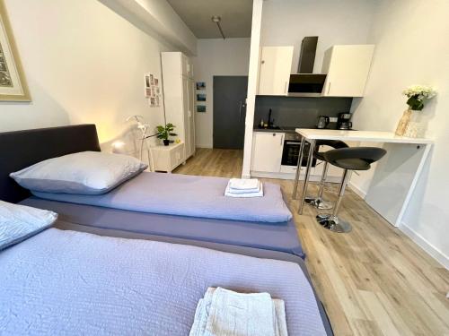 two beds in a small room with a kitchen at Neu wunderschönenes weißes Apartament am Schlössle Zentrum Goldstadt in Pforzheim