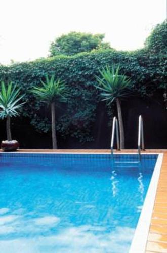 a blue swimming pool with palm trees in the background at Mercure North Melbourne in Melbourne