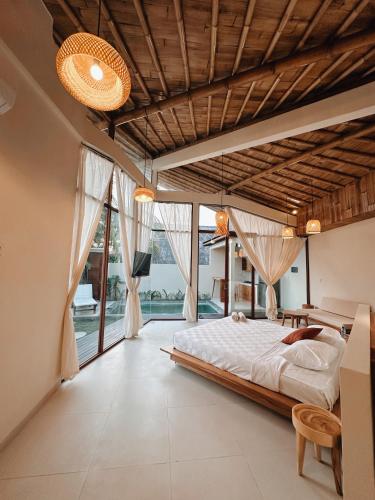 a bedroom with a large bed and large windows at Capila Villa Bali in Canggu
