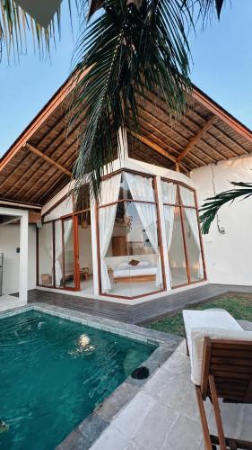 a villa with a swimming pool and a house at Capila Villa Bali in Canggu