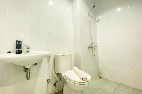 a white bathroom with a toilet and a sink at Comfort 1BR at Patraland Urbano Apartment By Travelio in Bekasi