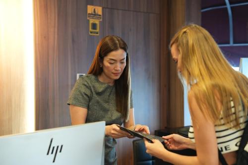two women standing in front of a computer at AG Hotel in Abu Dhabi
