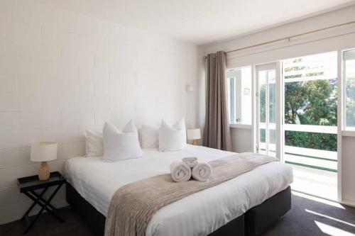 a bedroom with a large bed with two towels on it at Stay Mission Bay in Auckland