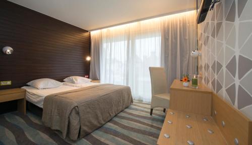 
a hotel room with a bed, chair, and nightstand at Hotel Maxim in De Panne
