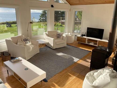 Una sala de estar con muebles blancos y un televisor. en Private Waterfront Luxury with Hot Tub and Barrel Sauna, en Sydney Forks