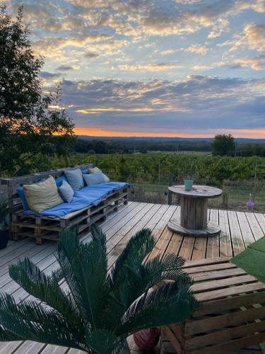 a patio with a couch and a table on a deck at Bubulles dans les vignes in Le Fieu