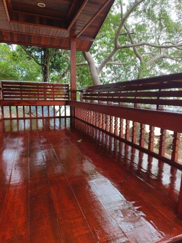 a wooden porch with a wooden floor and trees at Kohjum Seafront Resort in Ko Jum
