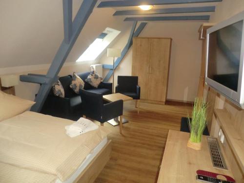 a room with a bed and chairs and a staircase at Hotel Pension Am Hafen in Norddeich