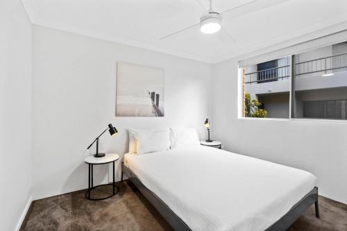 a white bedroom with a bed and a window at Salty Sea Breeze Apartment 500m to waters edge in Gold Coast