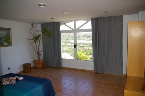 a bedroom with a blue bed and a large window at Precioso Loft de 100 m2 con vistas impresionantes - Alquiler de temporada in Gilet
