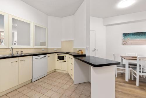 a kitchen with white cabinets and a black counter top at Charlesworth Bay Beach Resort in Coffs Harbour