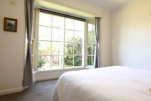 a bedroom with a bed and a large window at Hampton Spacious House & Pool in Melbourne