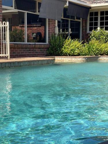 a pool of blue water in front of a house at Hampton Spacious House & Pool in Melbourne