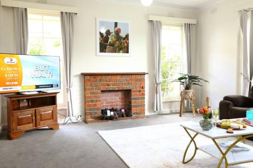 a living room with a tv and a brick fireplace at Hampton Spacious House & Pool in Melbourne