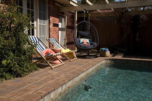 a couple of chairs sitting next to a swimming pool at Hampton Spacious House & Pool in Melbourne