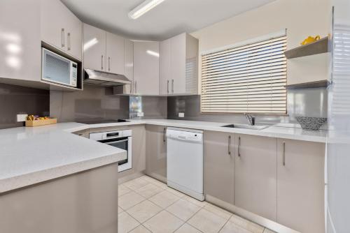a kitchen with white cabinets and white appliances at Charlesworth Bay Beach Resort in Coffs Harbour