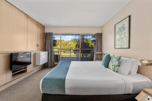 a hotel room with a large bed and a large window at Charlesworth Bay Beach Resort in Coffs Harbour