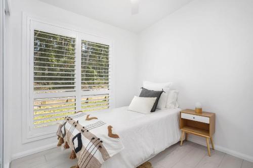 a white bedroom with a bed and a window at Clovelly - Book 3 nights, pay for 2! in St Georges Basin