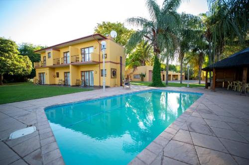 a house with a swimming pool in front of a house at Sunriver Kalahari Lodge Riverside stay in Upington in Upington