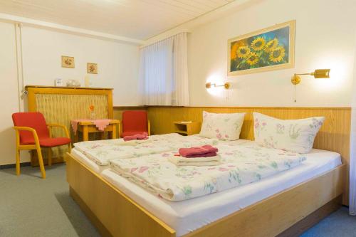 a bedroom with a large bed with two red chairs at Pension Haus Brückner in Wildemann