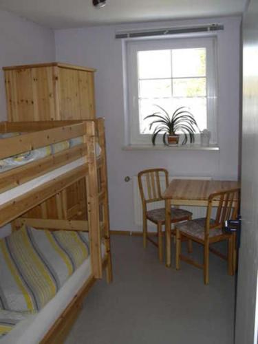a bedroom with a bunk bed and a table and chair at Ferienwohnung "Haus Tanneck" in Clausthal-Zellerfeld