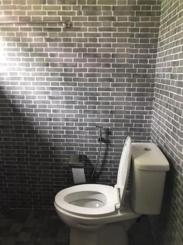 a bathroom with a white toilet and a brick wall at บ้านชมธาร บ้านสวนสราญชล in Ban Plai Nam (2)