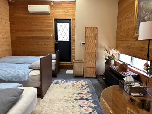 a bedroom with two beds and a table and a door at 一棟貸しの朋友 in Zentsuji