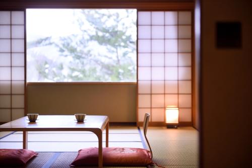 a room with a table and a chair and a window at Urabandai Lake Resort Goshiki no Mori in Kitashiobara