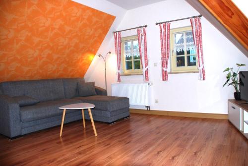 a living room with a couch and two windows at FH Am Osterbrunnen in Hinterhermsdorf
