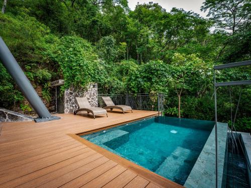 a swimming pool on a wooden deck with chairs at Suitree Experience Hotel in Guanacaste