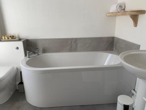a white bath tub in a bathroom with a sink at The Cow Shed at Bank Farm in Yeovil