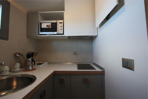 a small kitchen with a sink and a microwave at Hotel & Residence Cavalluccio Marino in Rimini
