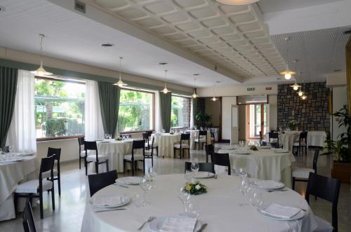 a dining room with white tables and chairs and windows at Hotel Bassetto in Ferentino