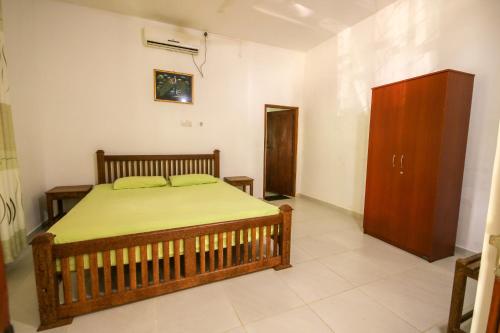 Un dormitorio con una cama y un armario de madera. en Deluxe Double Room, en Unawatuna