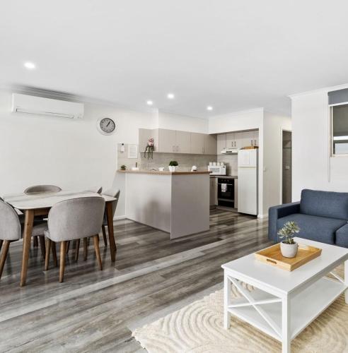 a living room and kitchen with a blue couch and a table at Yarrawonga Lakeside Apartment 27 in Mulwala