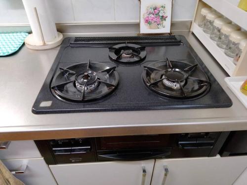 a stove top with three burners on a kitchen counter at 里の家 in Okuma