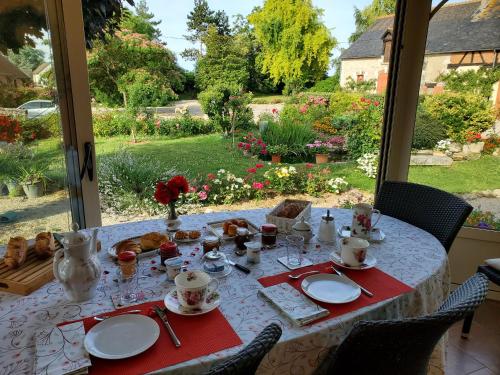 a table with plates of food and a view of a garden at Chambre coquelicot in Marchenoir