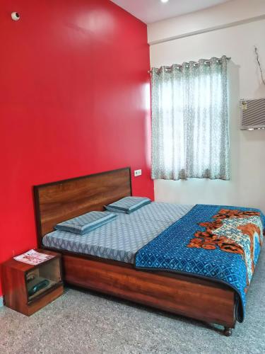 a bedroom with a bed with a red wall at Prem Bhawan Guest House in Khātu